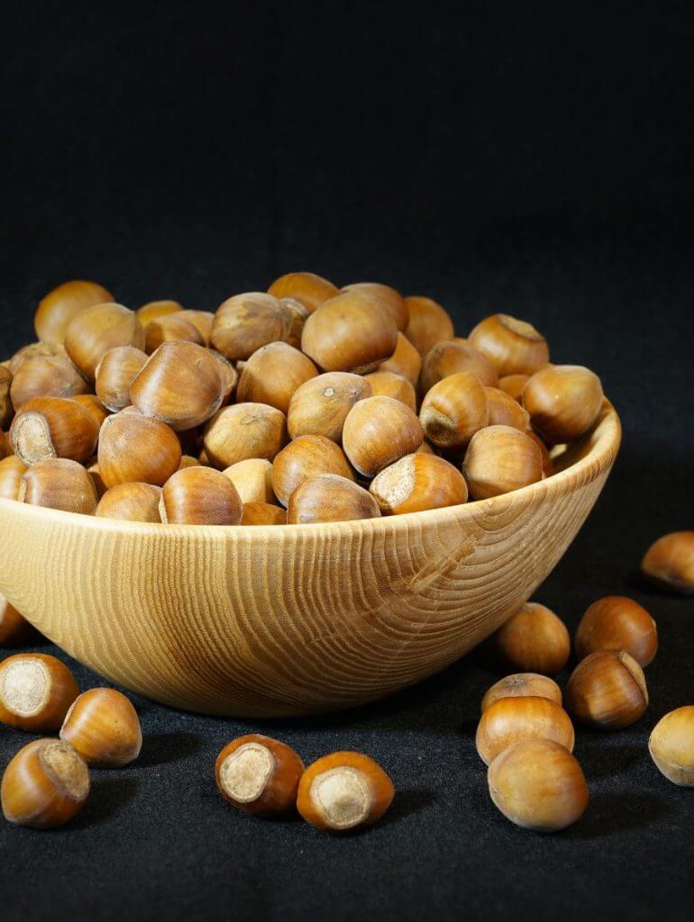 Fresh hazelnuts in shell and shelled on wooden bowl