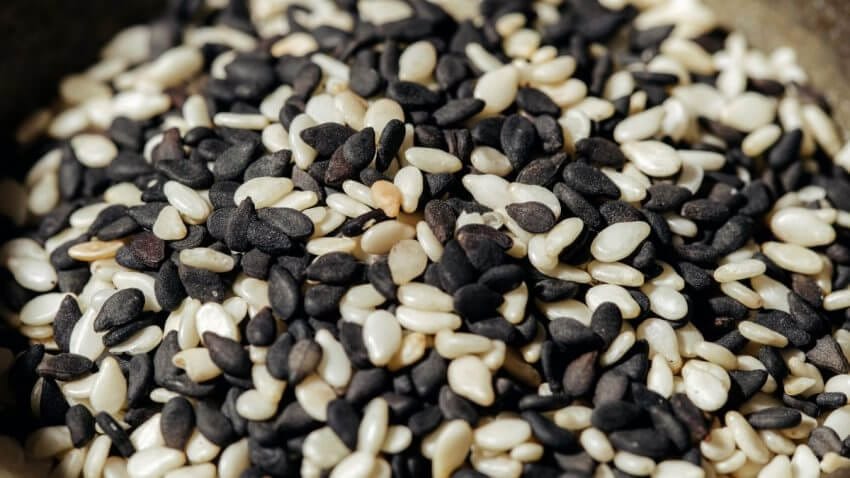 White and black sesame seeds in bowls (unhulled and hulled)