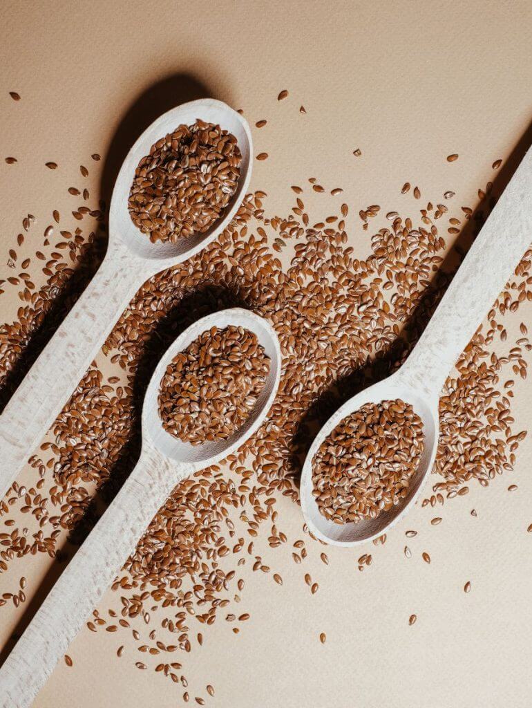 Brown and golden flax seeds on white spoon