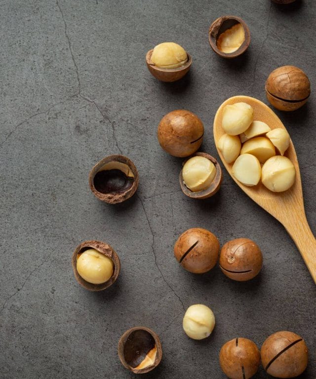 Whole and cracked macadamia nuts showing creamy white kernels